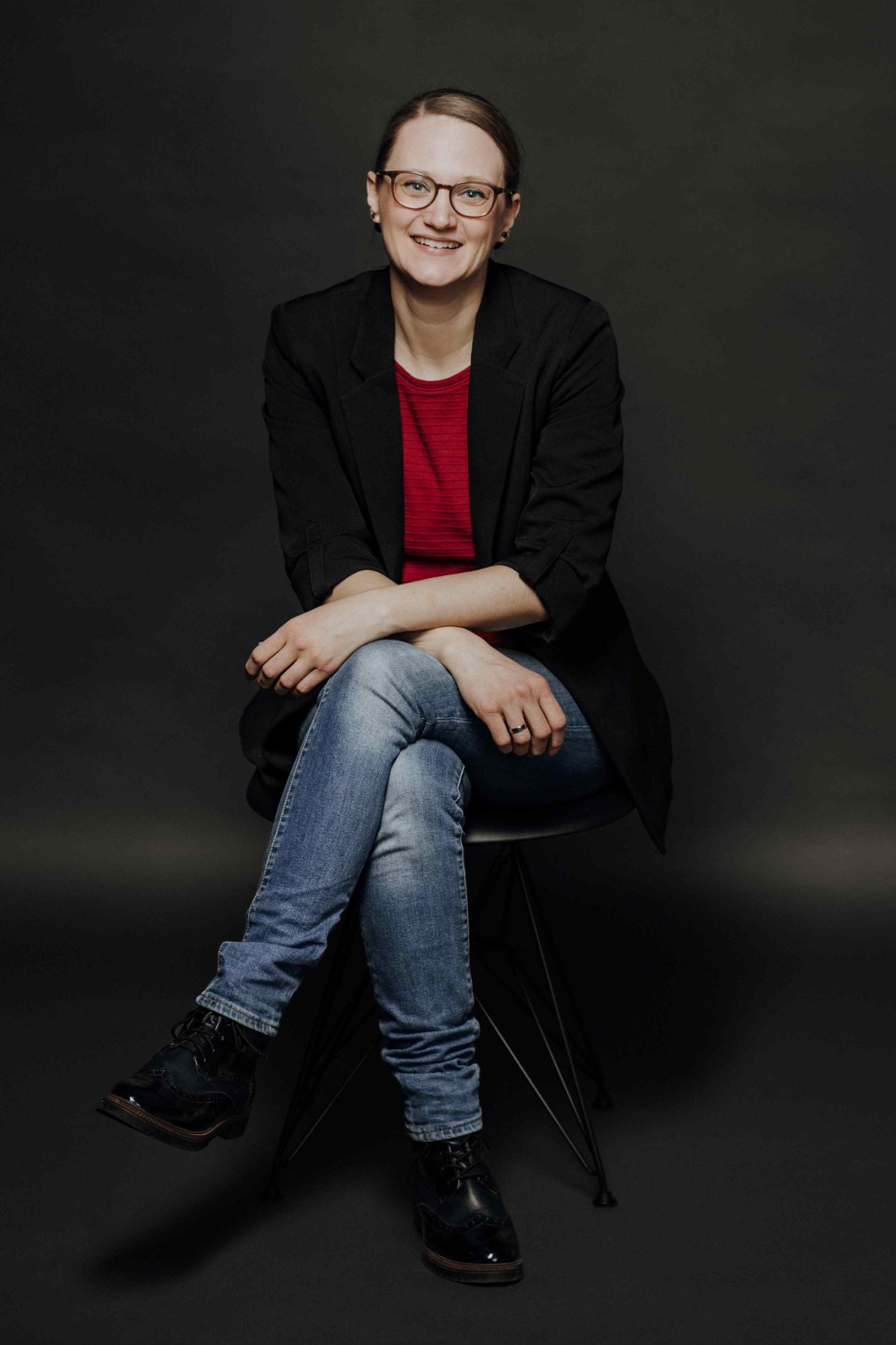 Bauleiter Hochbau Arndt Rousek Mann sitzt lächelnd auf einem Stuhl, trägt ein kariertes Hemd und Jeans.