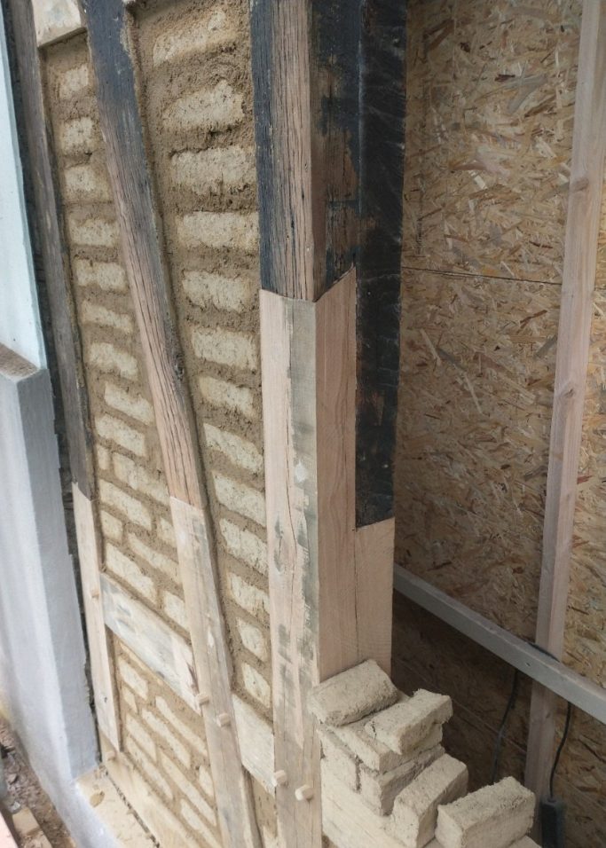Holzinstandsetzung und Lehmstein-Ausfachung bei historischem Fachwerk Fachwerksanierung mit Holzaustausch am Ständerwerk und traditioneller Ausfachung durch rohe Lehmsteine.