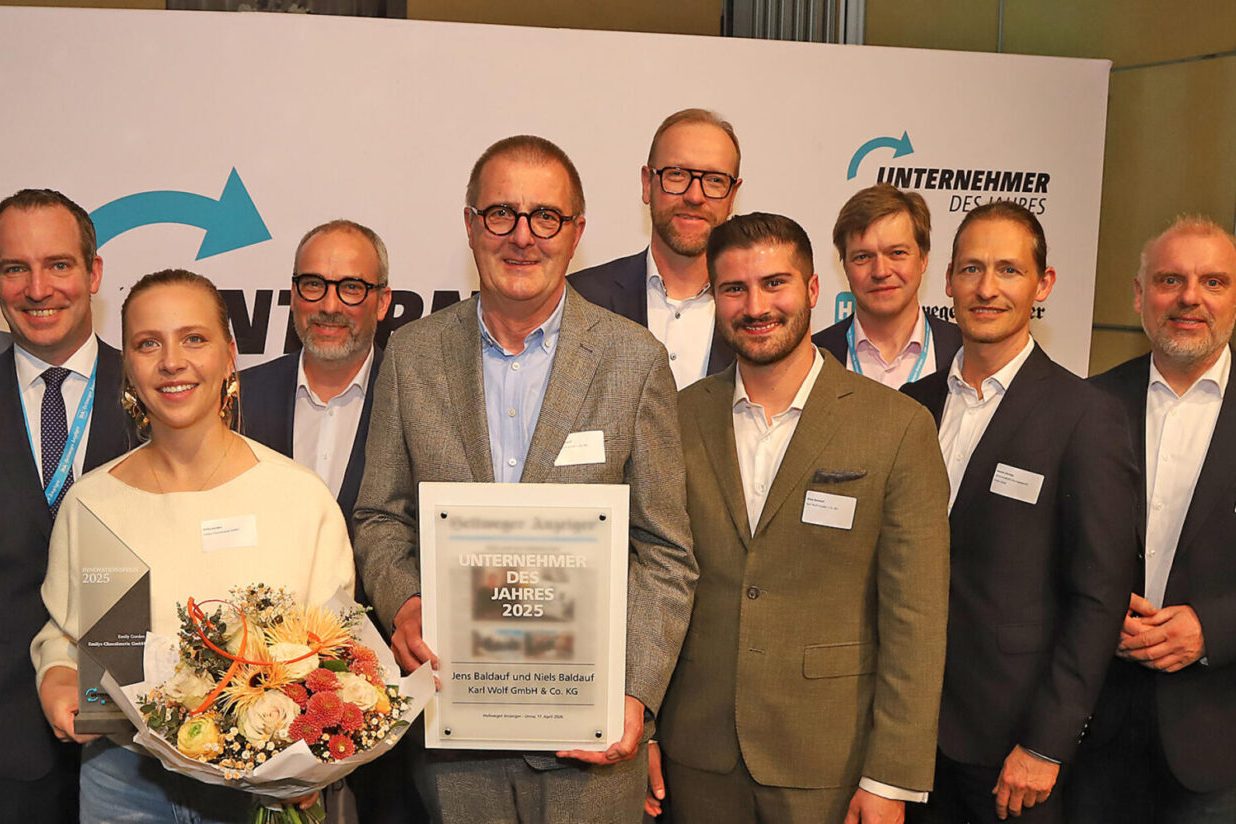 Verleihung Unternehmer des Jahres 2025 Gruppe von Personen mit Urkunde und Blumen bei einer Preisverleihung.