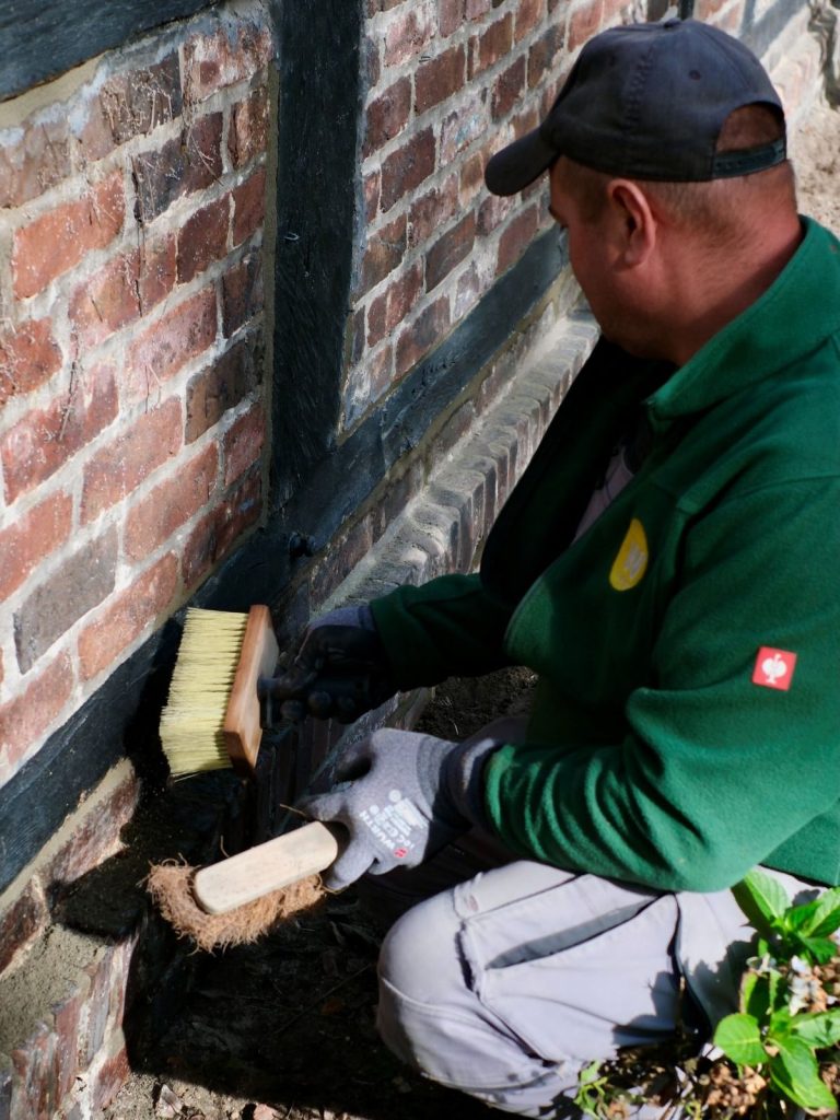 Oberflächenbearbeitung der frischen Fugen im zweistufigen Besenstrichverfahren Handwerker bearbeitet die neu verfugte Klinkerwand mit zwei unterschiedlichen Handbesen zur Verdichtung und sauberen Oberflächenstrukturieru