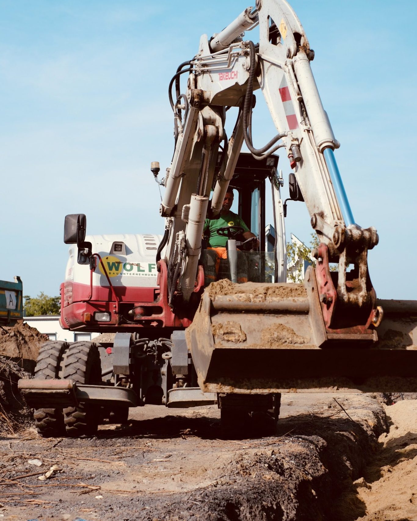 Einsatz des Mobilbaggers Bagger arbeitet im Boden und hebt Sand über eine Rohrleitung.